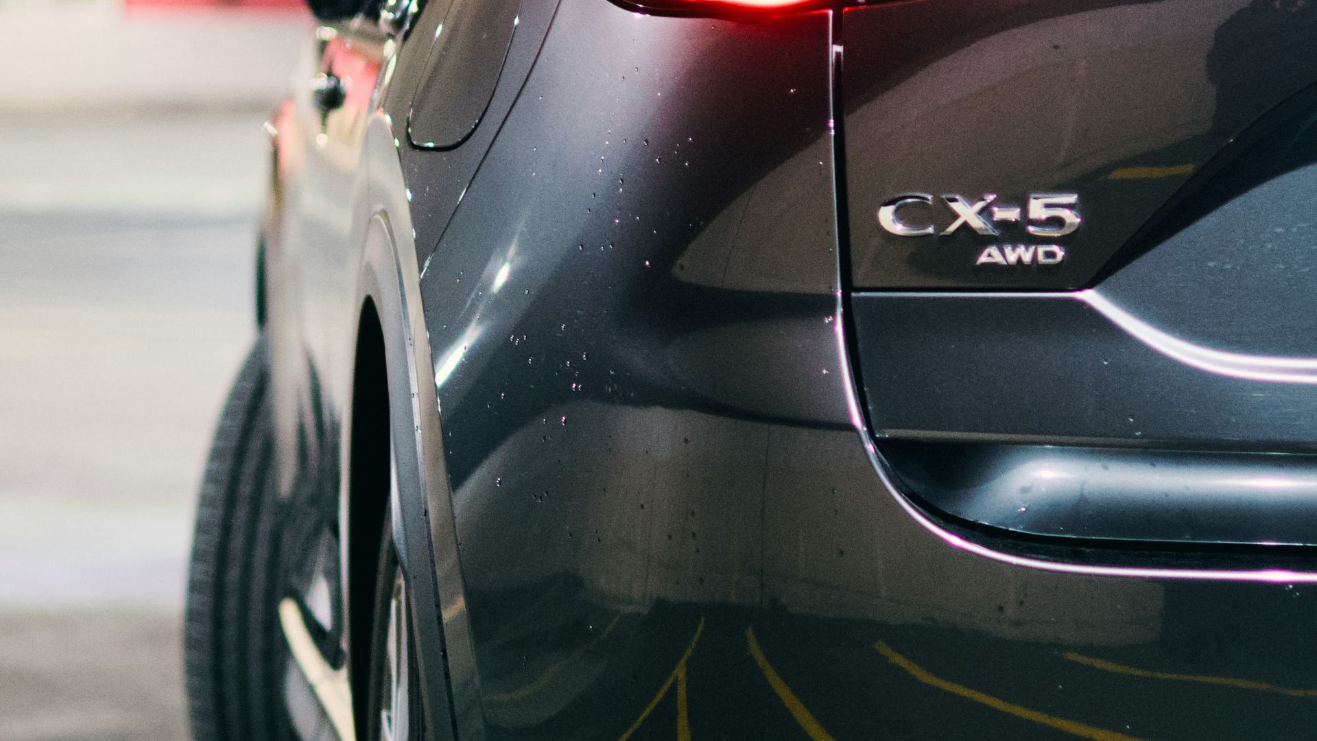 A dark suv's rear taillight glows in the parking garage.
