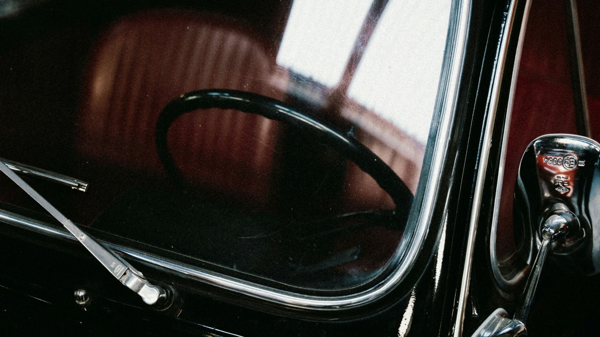 A black car parked in a garage next to another car