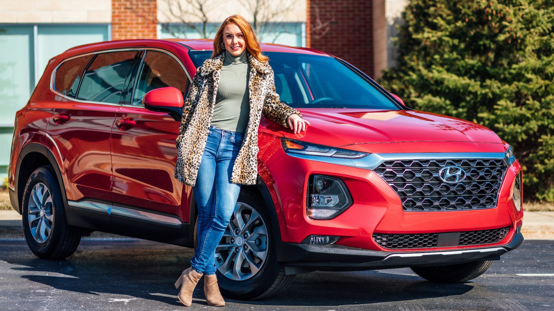woman in white and black scarf and blue denim jeans standing beside red mercedes benz car