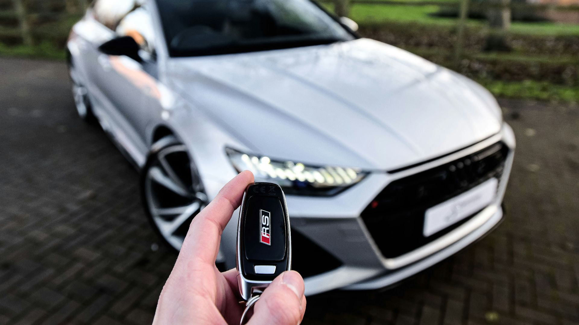 a person holding a car key in front of a silver car