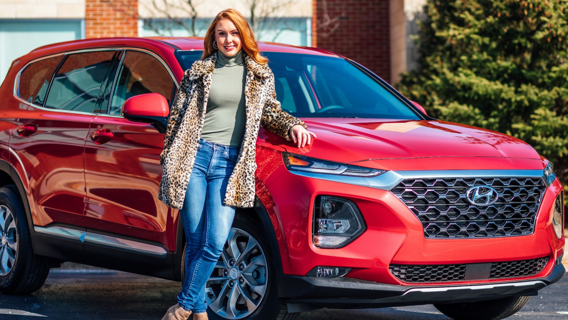 woman in white and black scarf and blue denim jeans standing beside red mercedes benz car