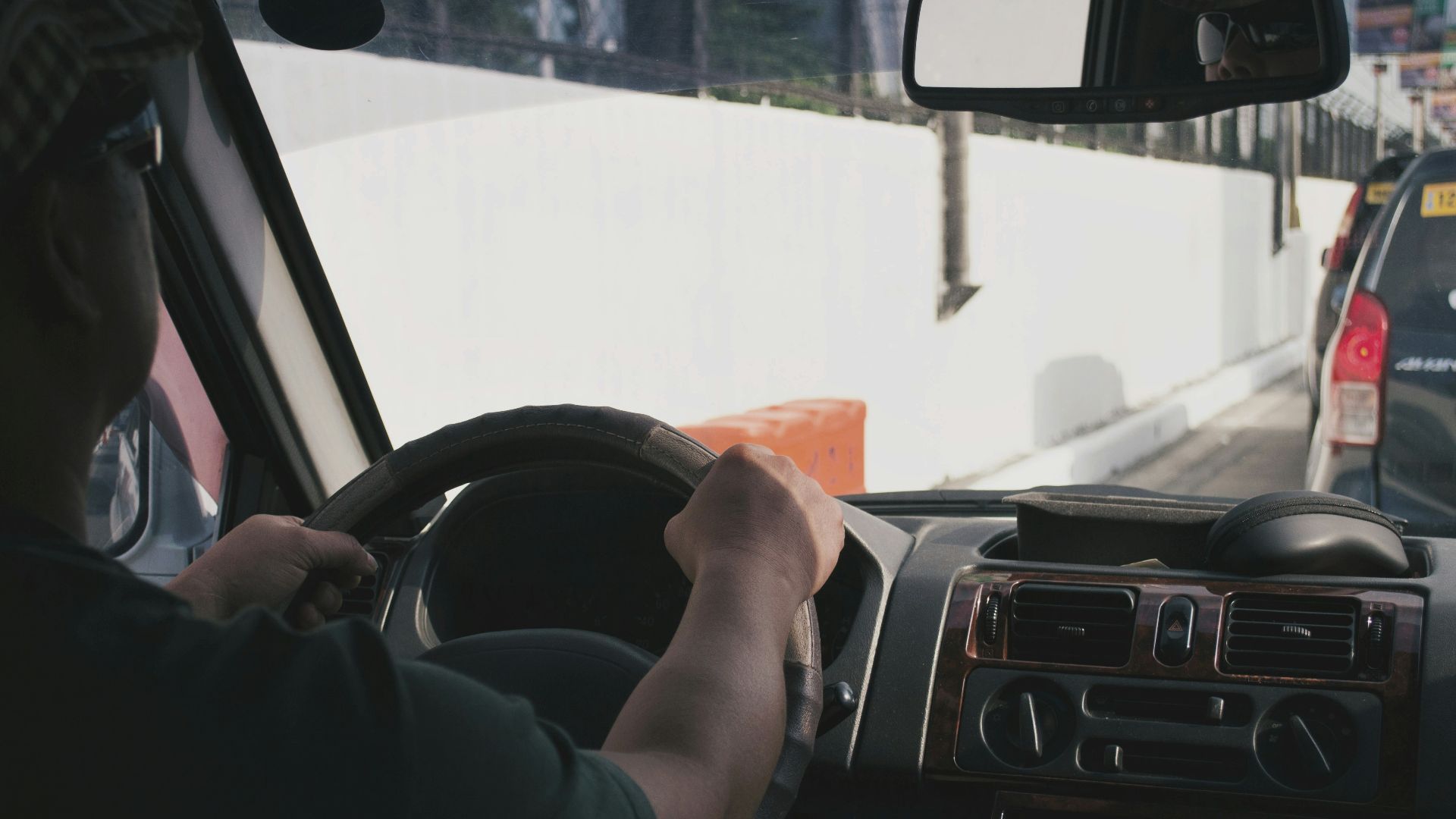 person driving vehicle on road near vehicle at daytime