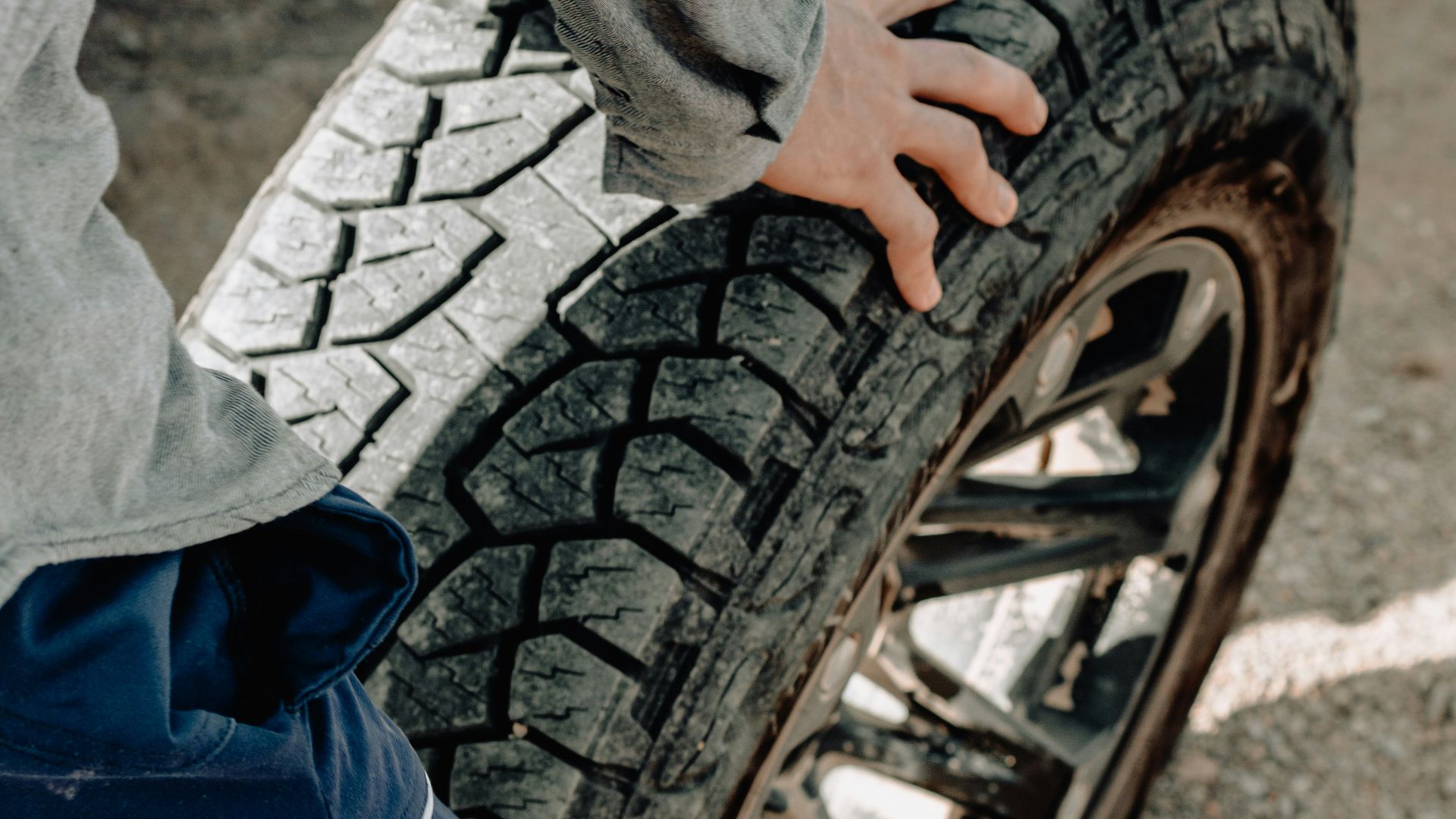 person holding vehicle wheel and rim