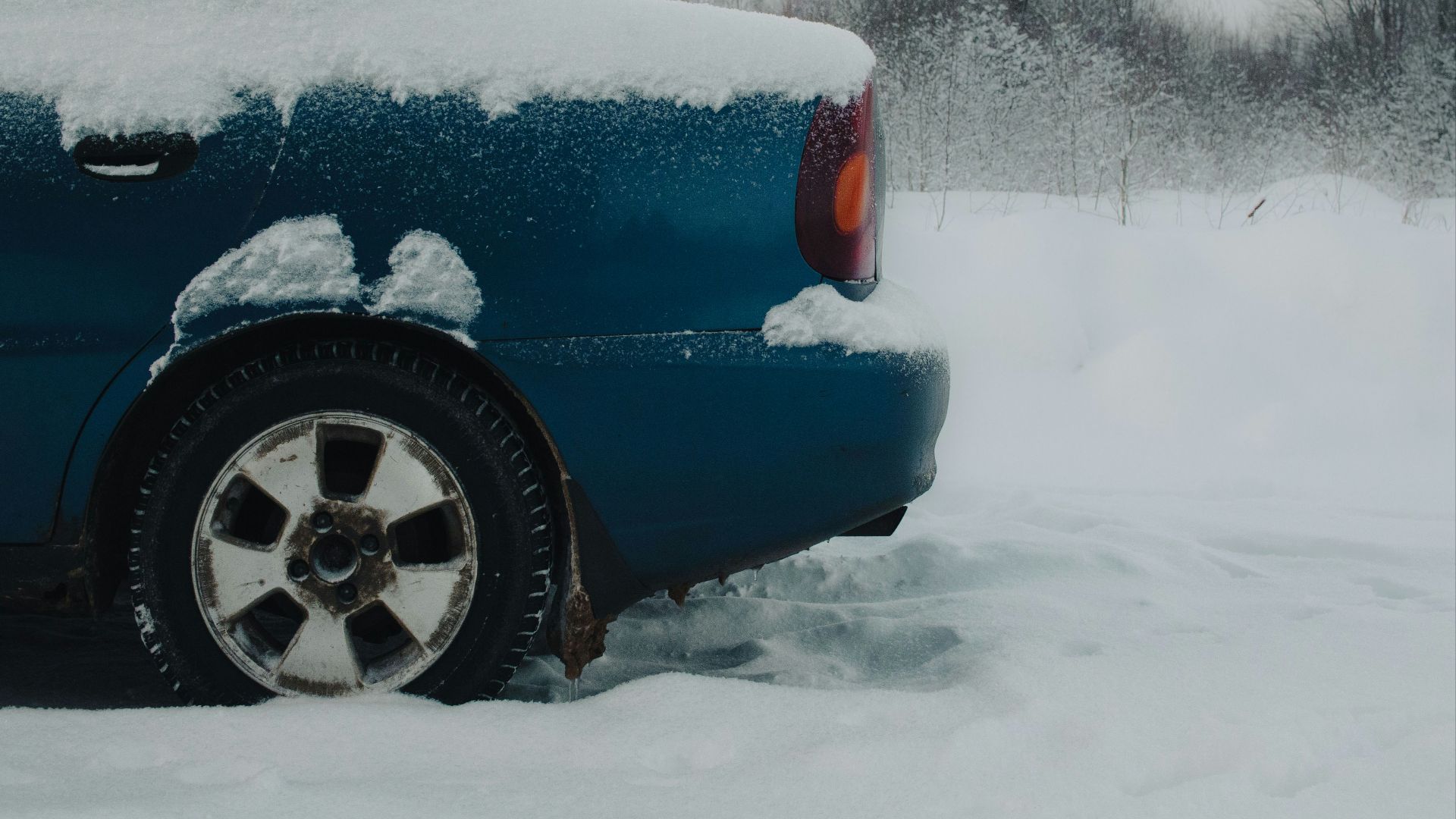 a blue car covered in snow on a snowy day