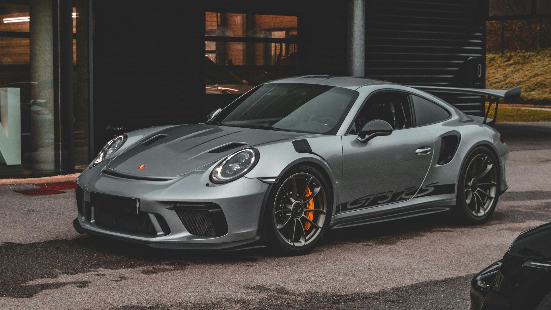 a grey porsche gtr parked in front of a building