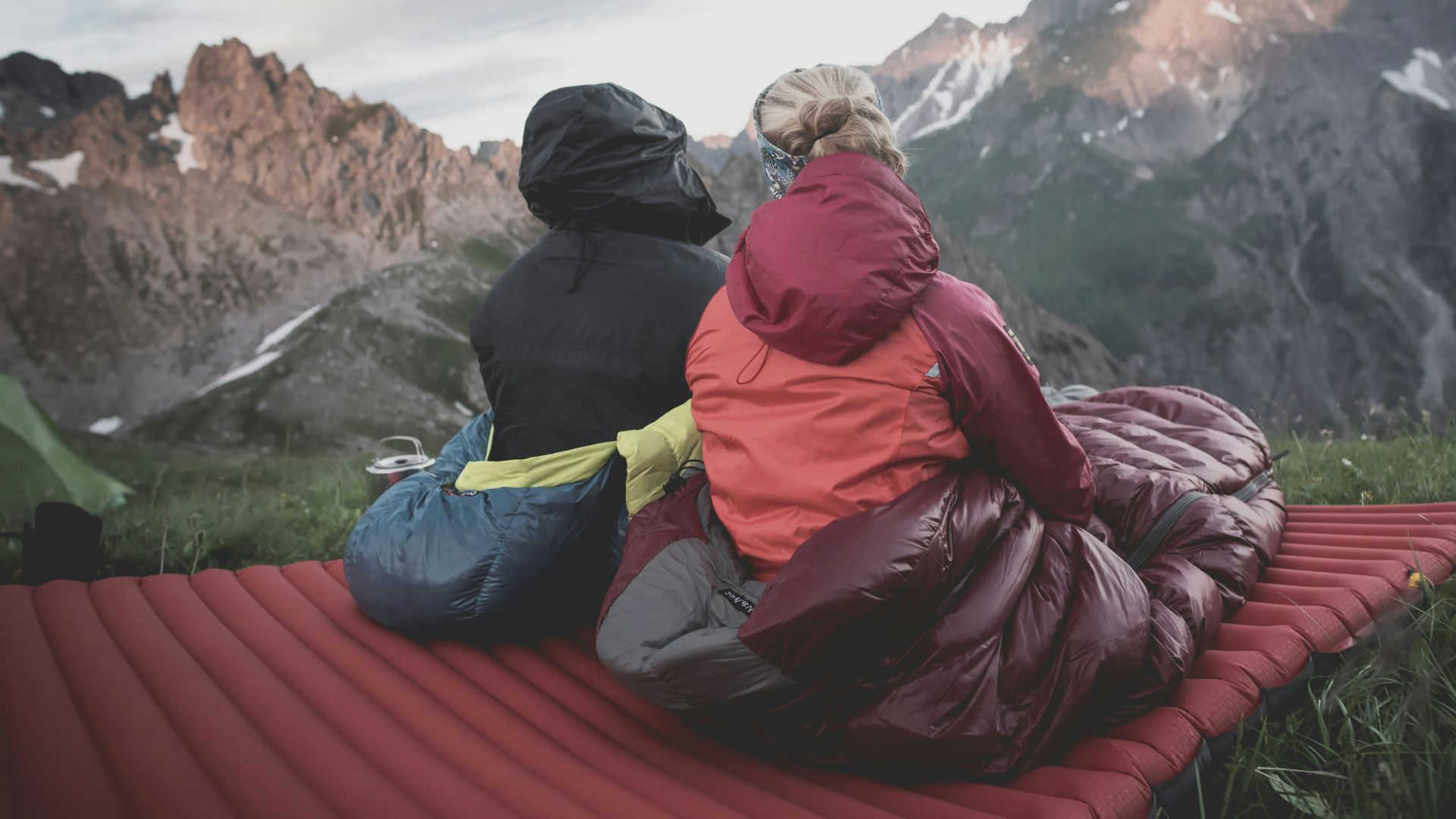 a couple of people sitting on top of a red blanket