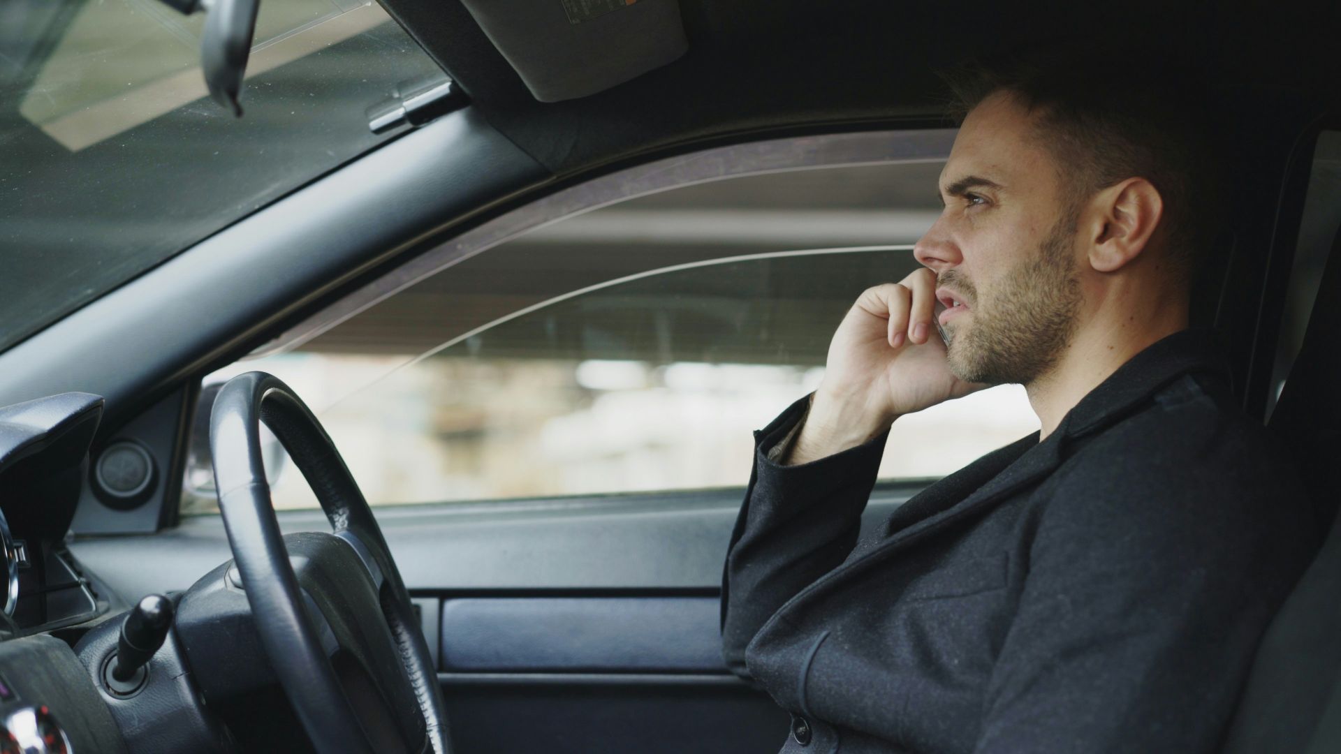 Man in suit talking on phone inside car
