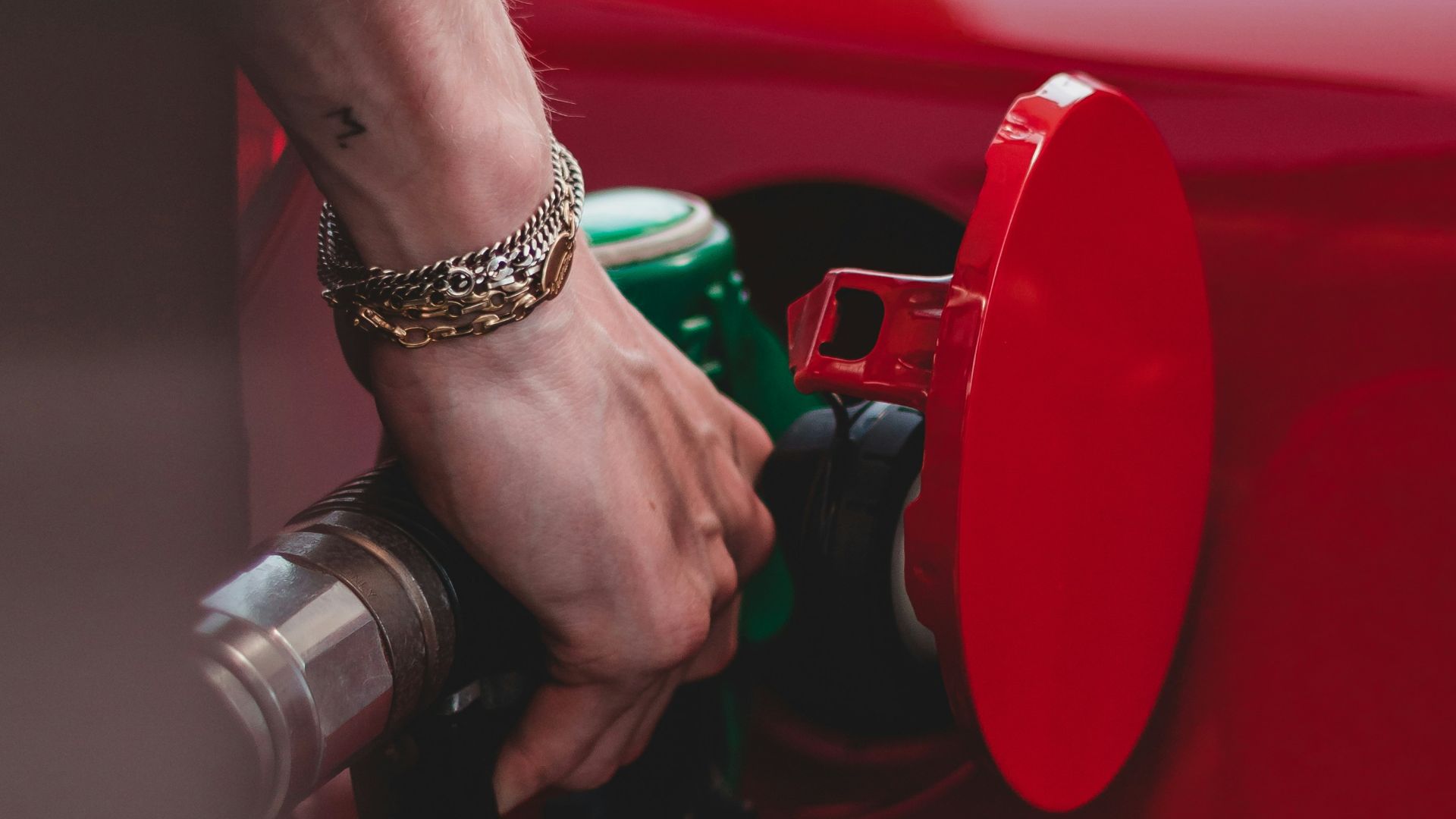 person in red shirt wearing silver bracelet holding red and black metal tool