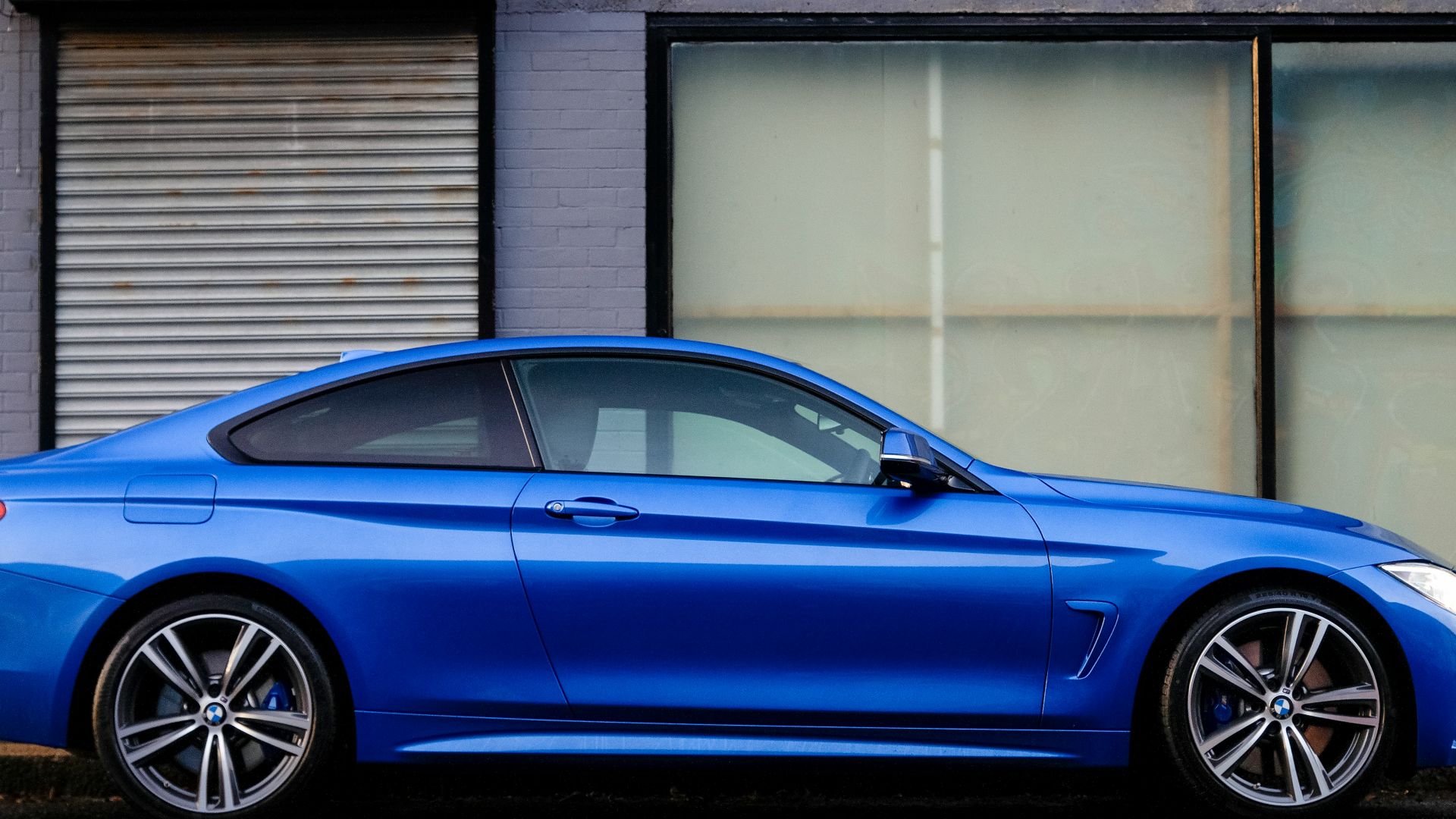 blue coupe beside gray house