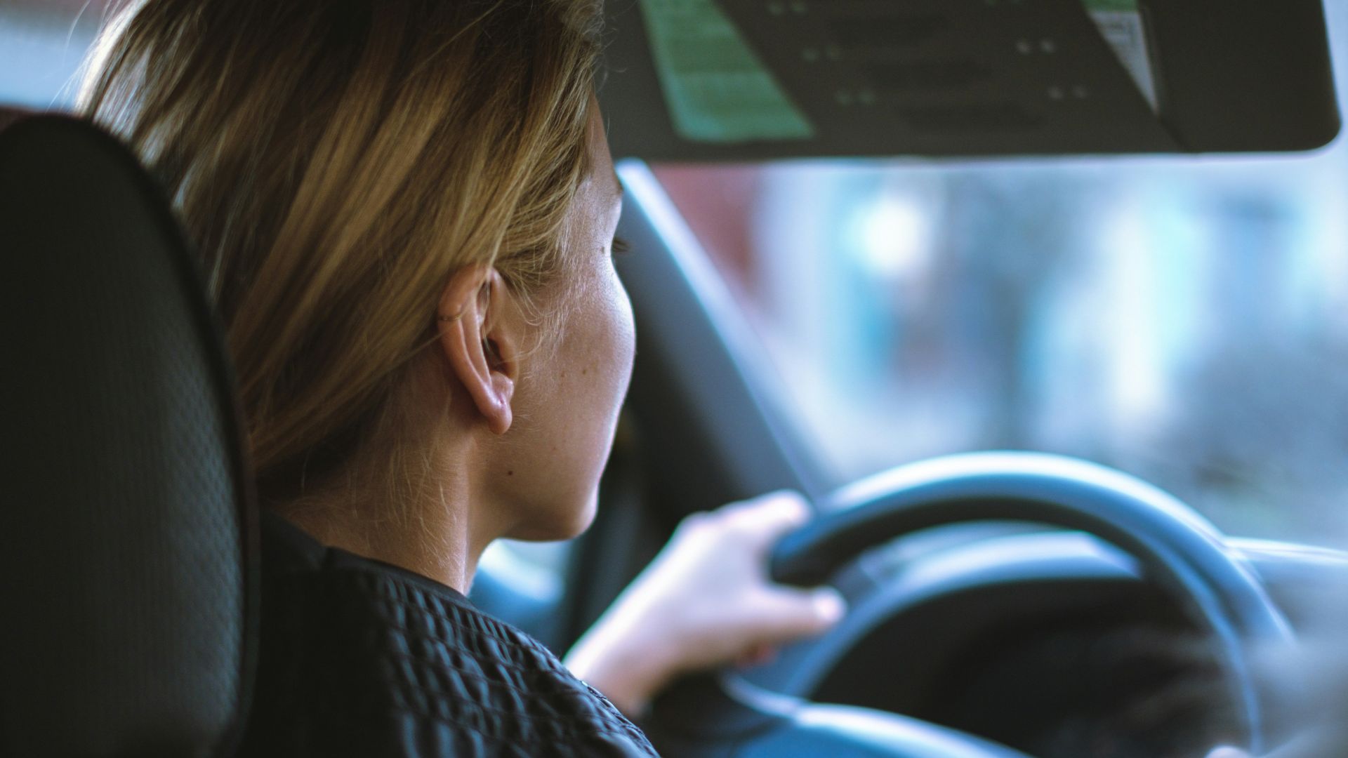 a woman sitting in a car with a steering wheel