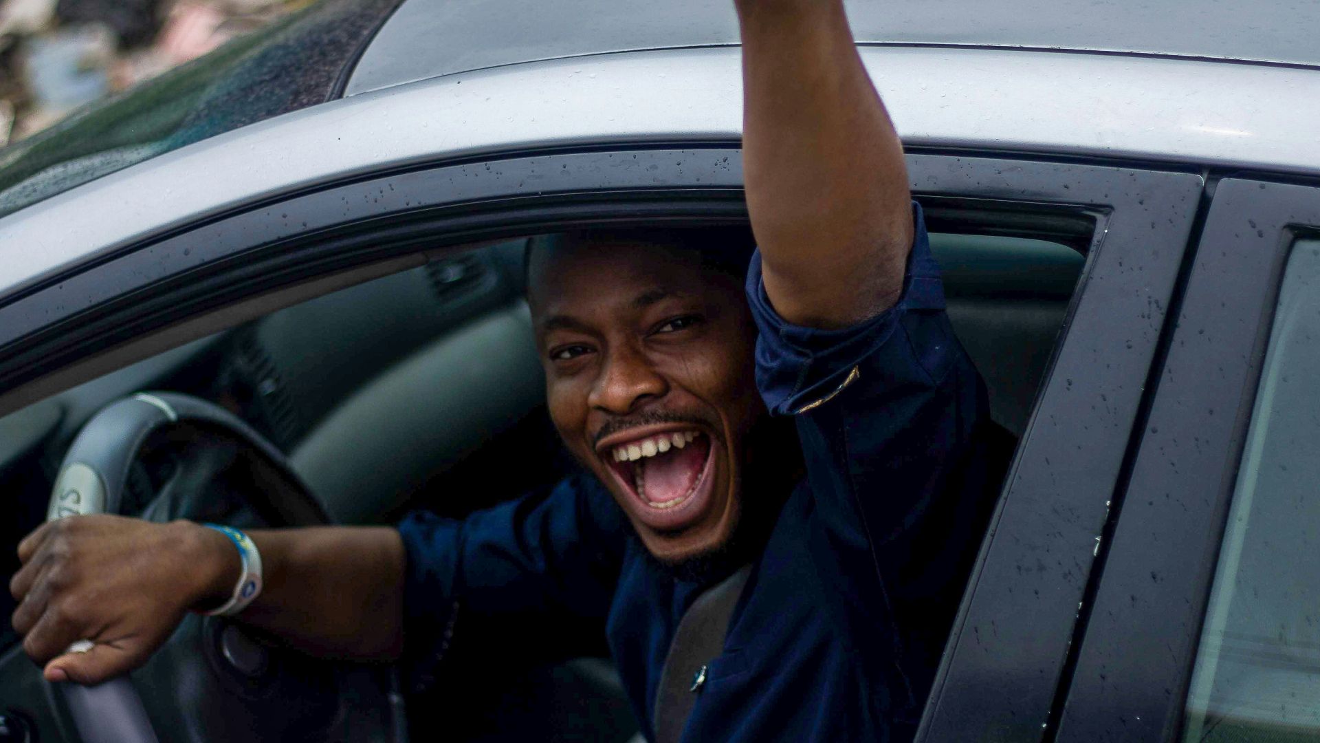 man in black t-shirt and blue denim jeans sitting on car seat