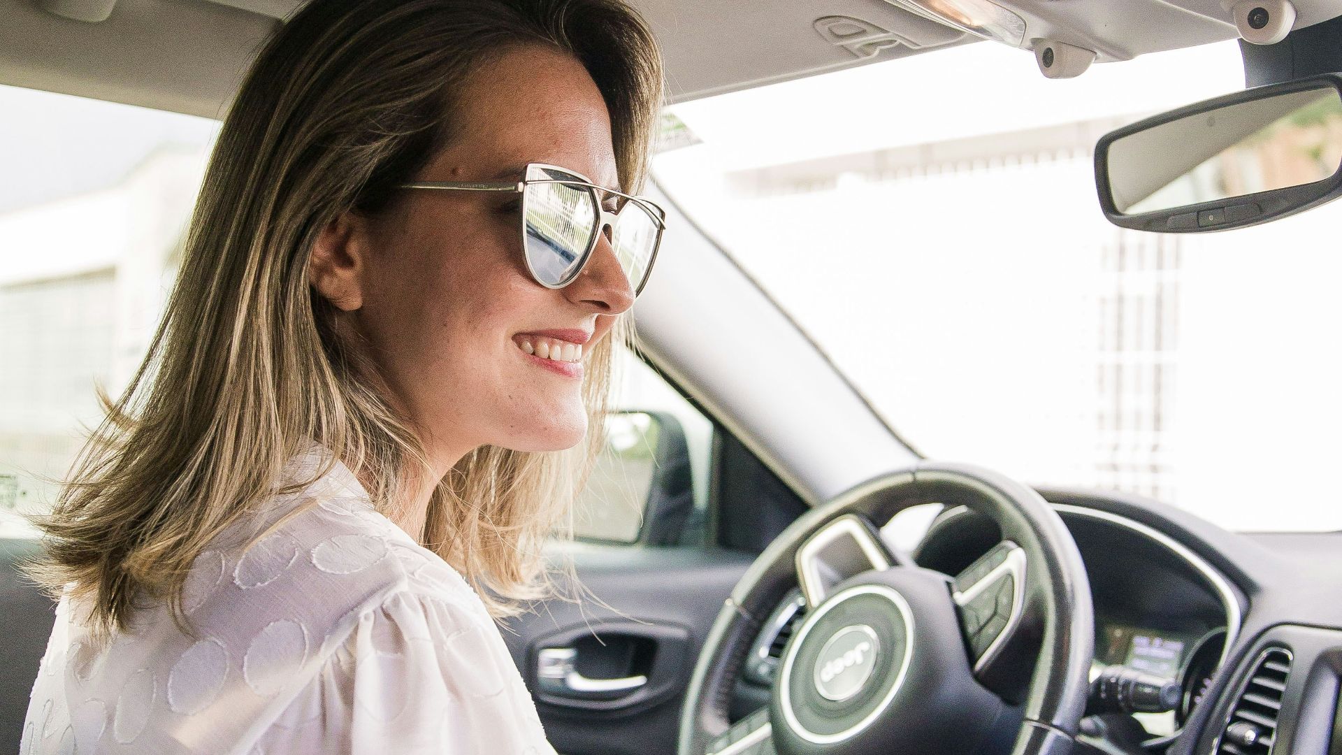 woman in white long sleeve shirt driving car