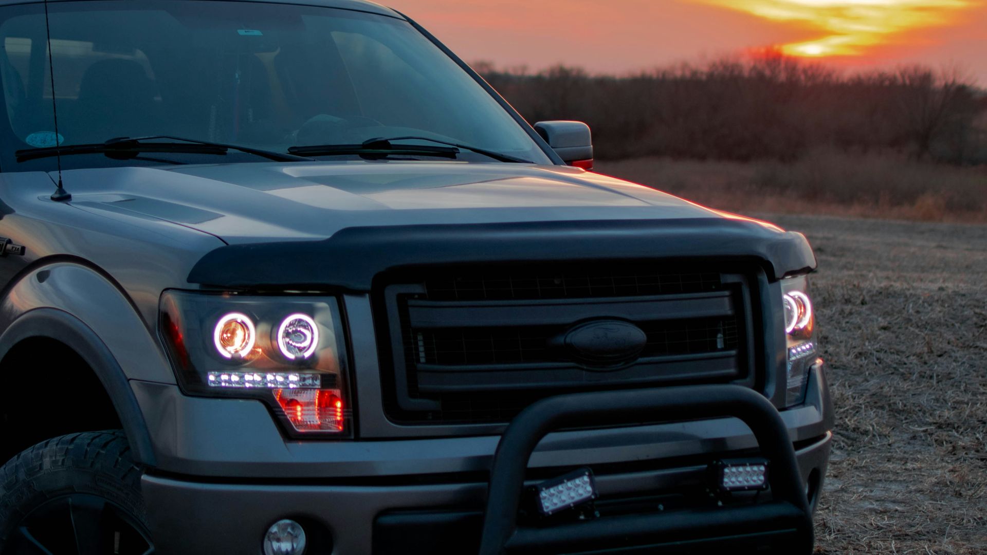 a truck parked in a field with a sunset in the background