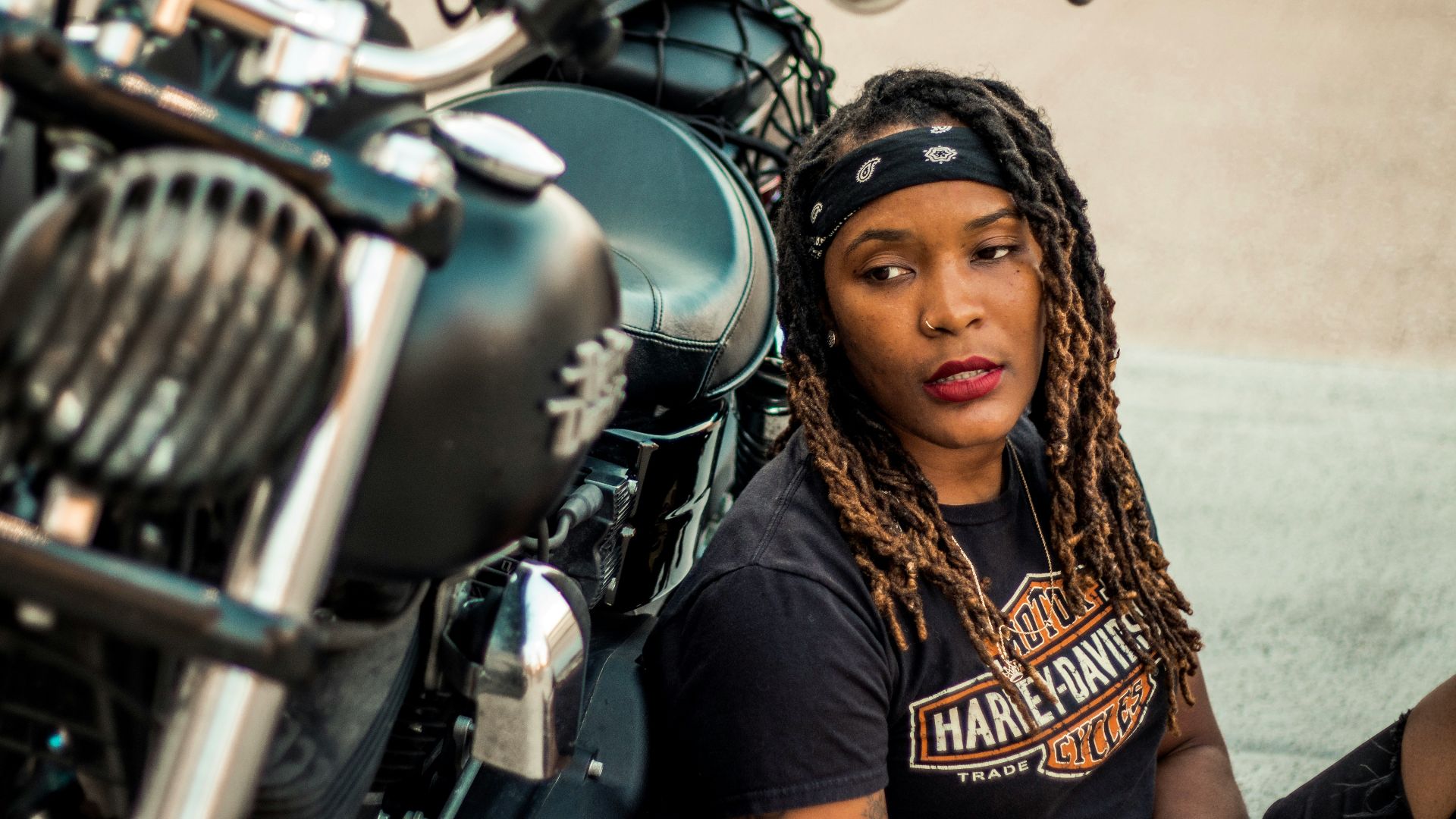woman in black top leaning on motorcycle