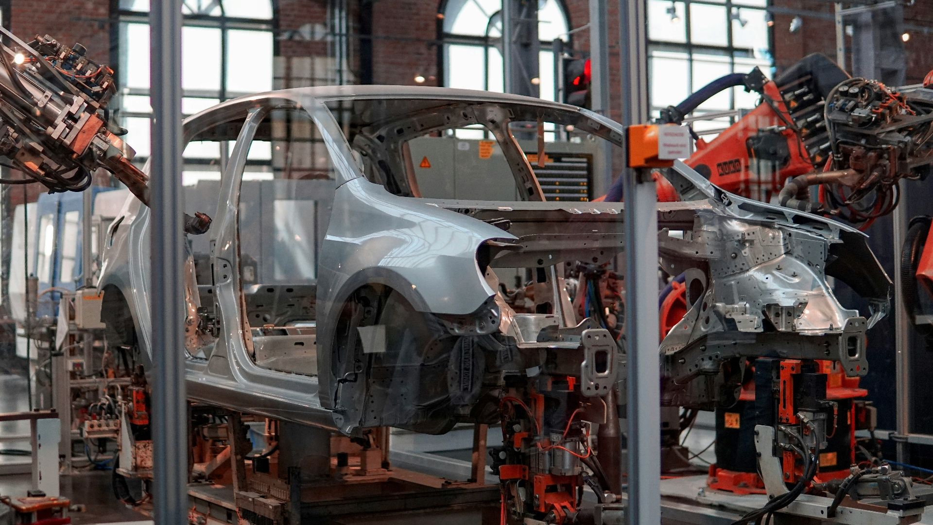 gray vehicle being fixed inside factory using robot machines