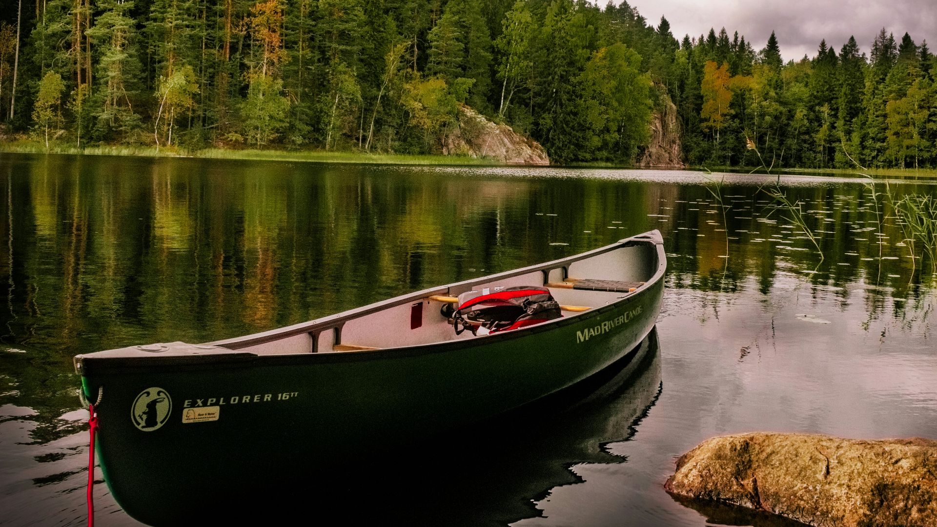 red and white canoe on lake near green trees under white clouds during daytime