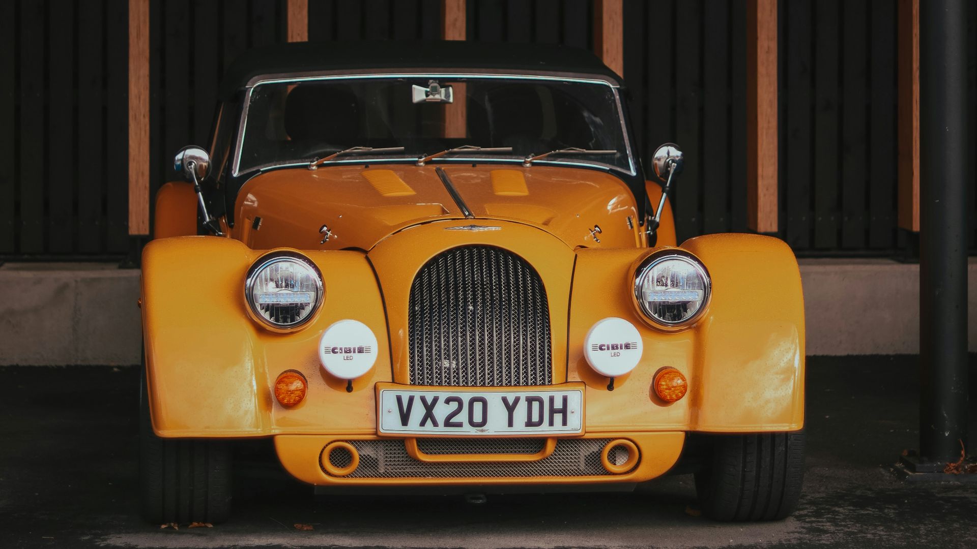 a yellow car parked under a wooden structure