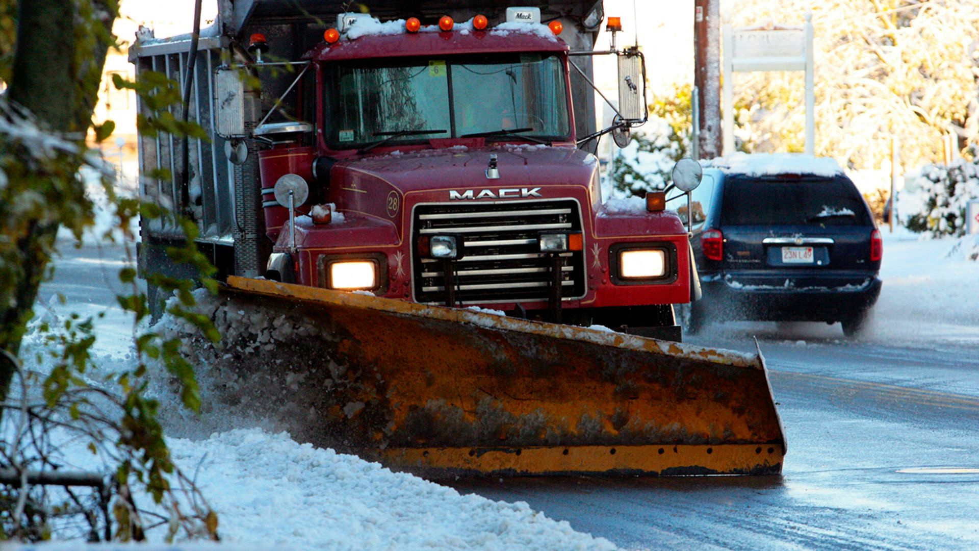 a snow plow driving down a snow covered road