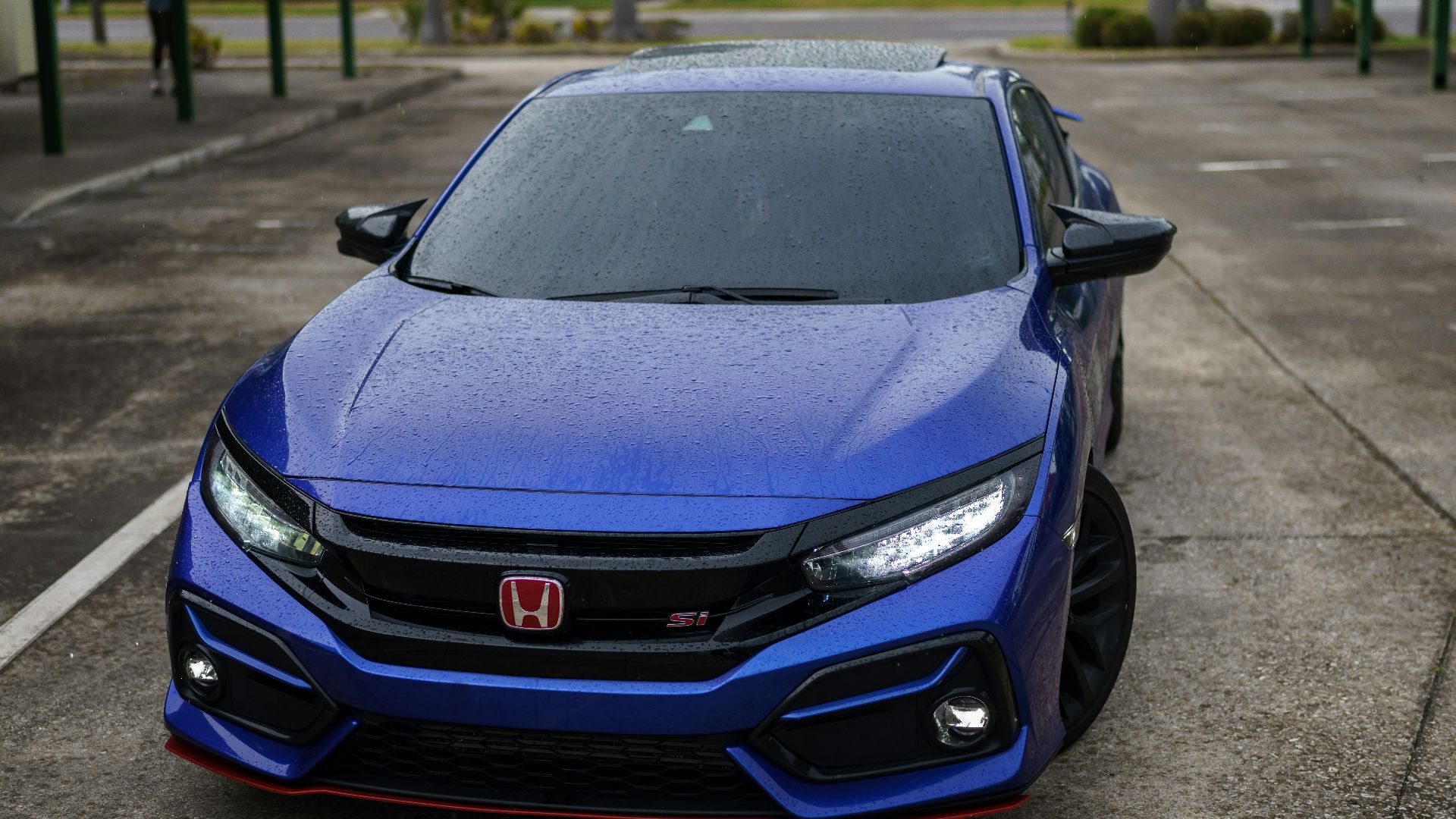 a blue sports car parked on a street with palm trees and a building