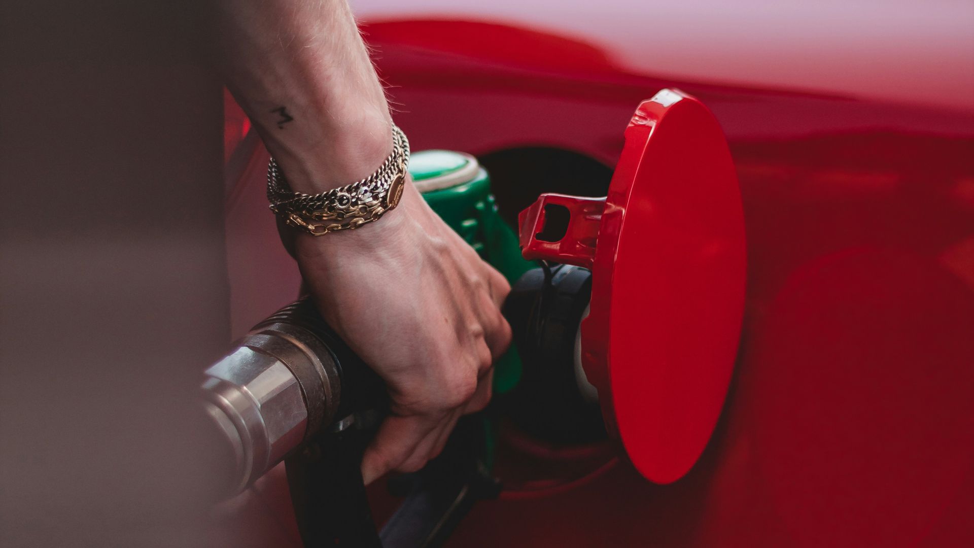 person in red shirt wearing silver bracelet holding red and black metal tool