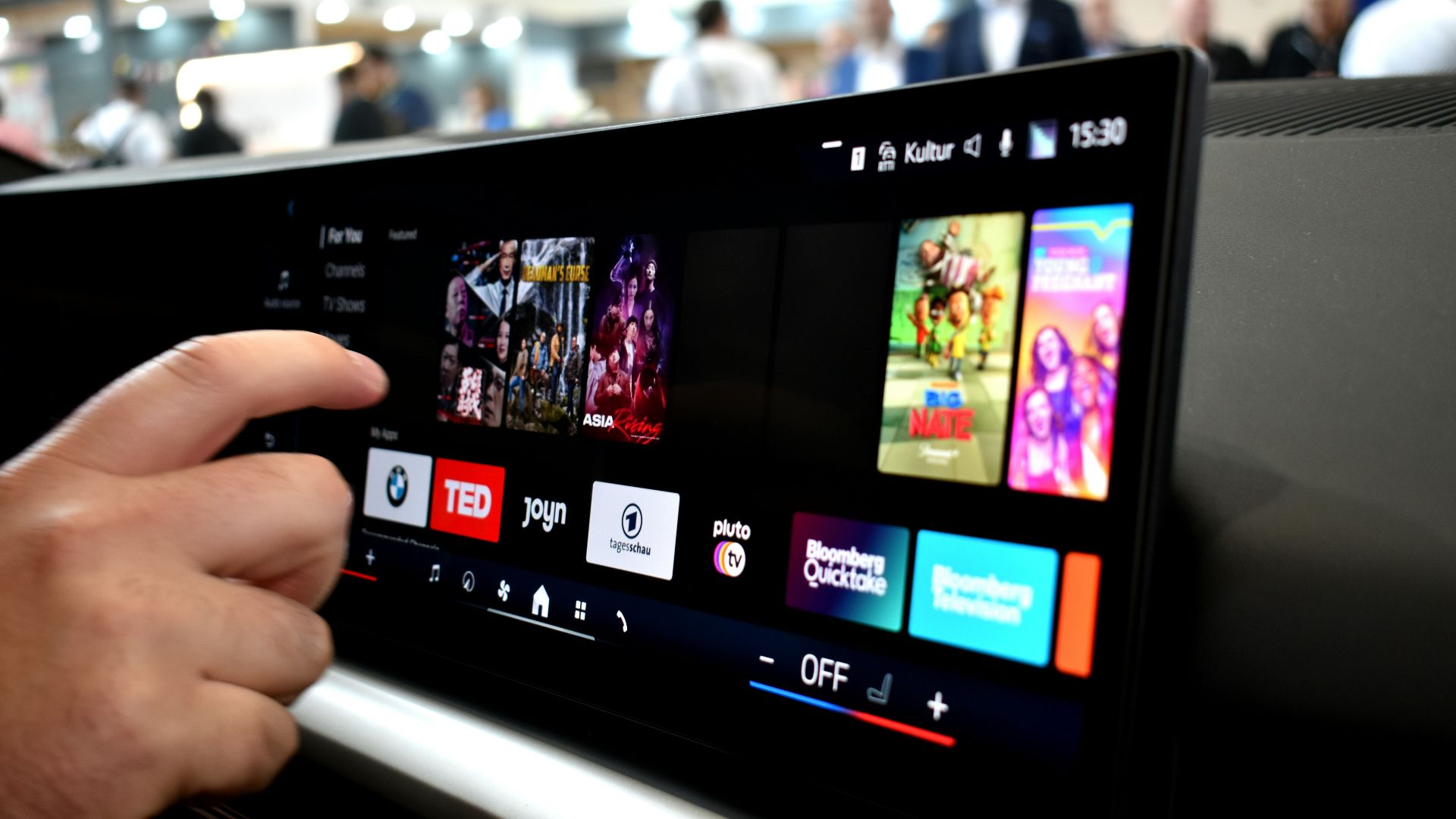 Person touching a car infotainment screen with media options.