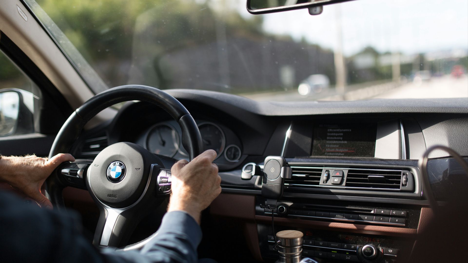 person holding BMW steering wheel