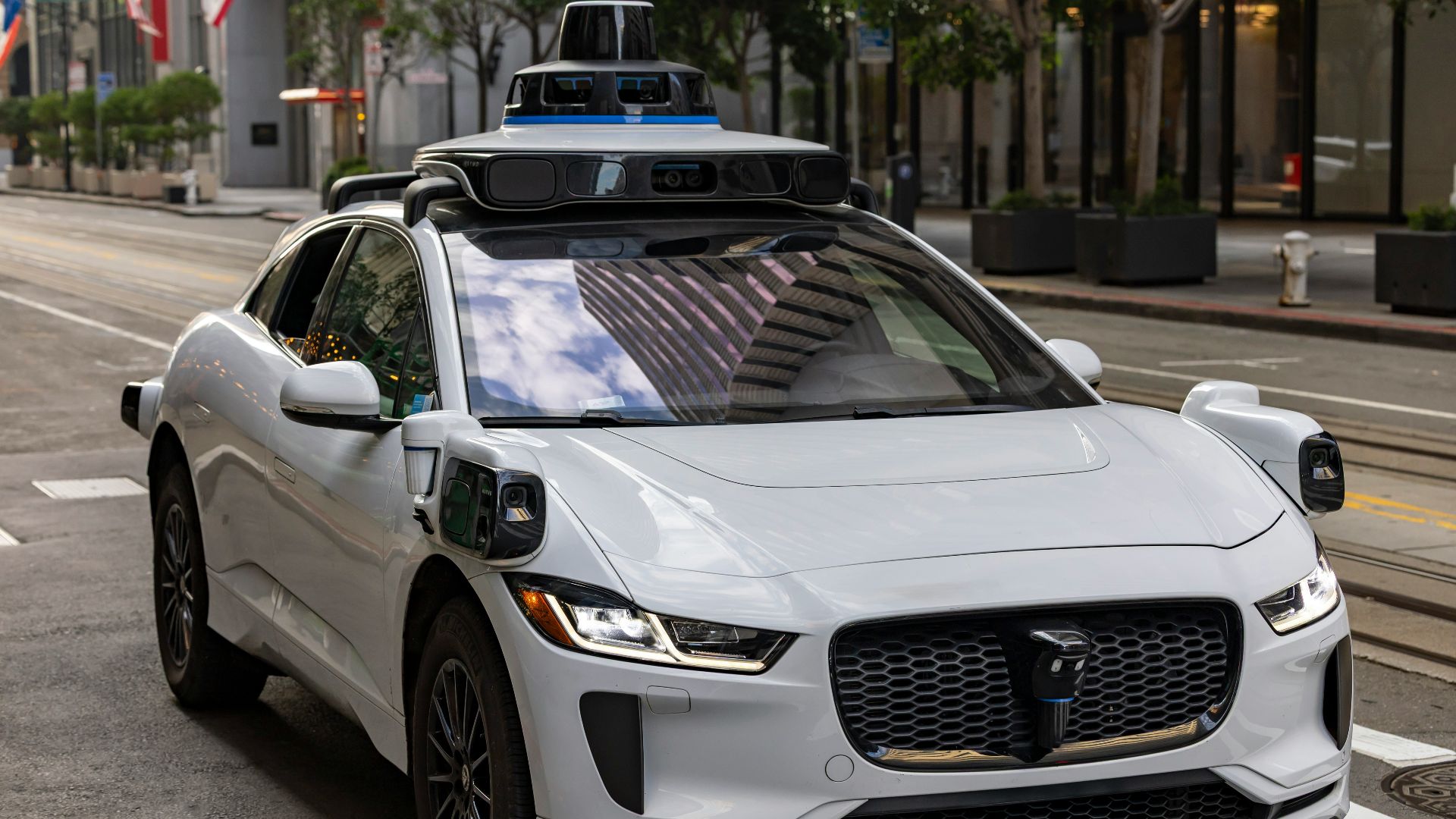 A white self-driving car on a city street.