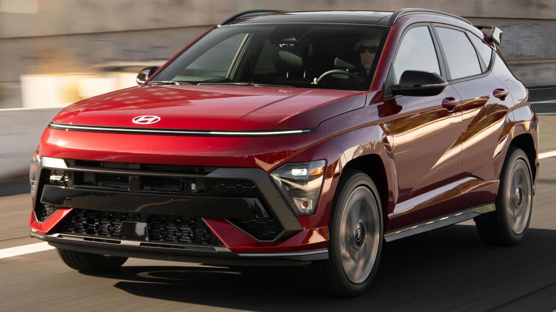 A red car driving down a street next to a building