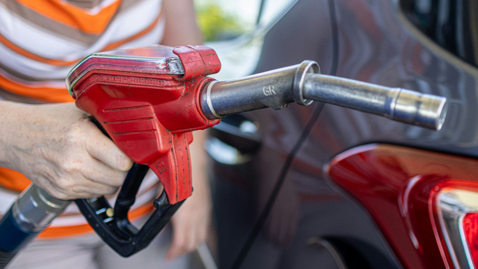 a woman filling a car with gas at a gas station