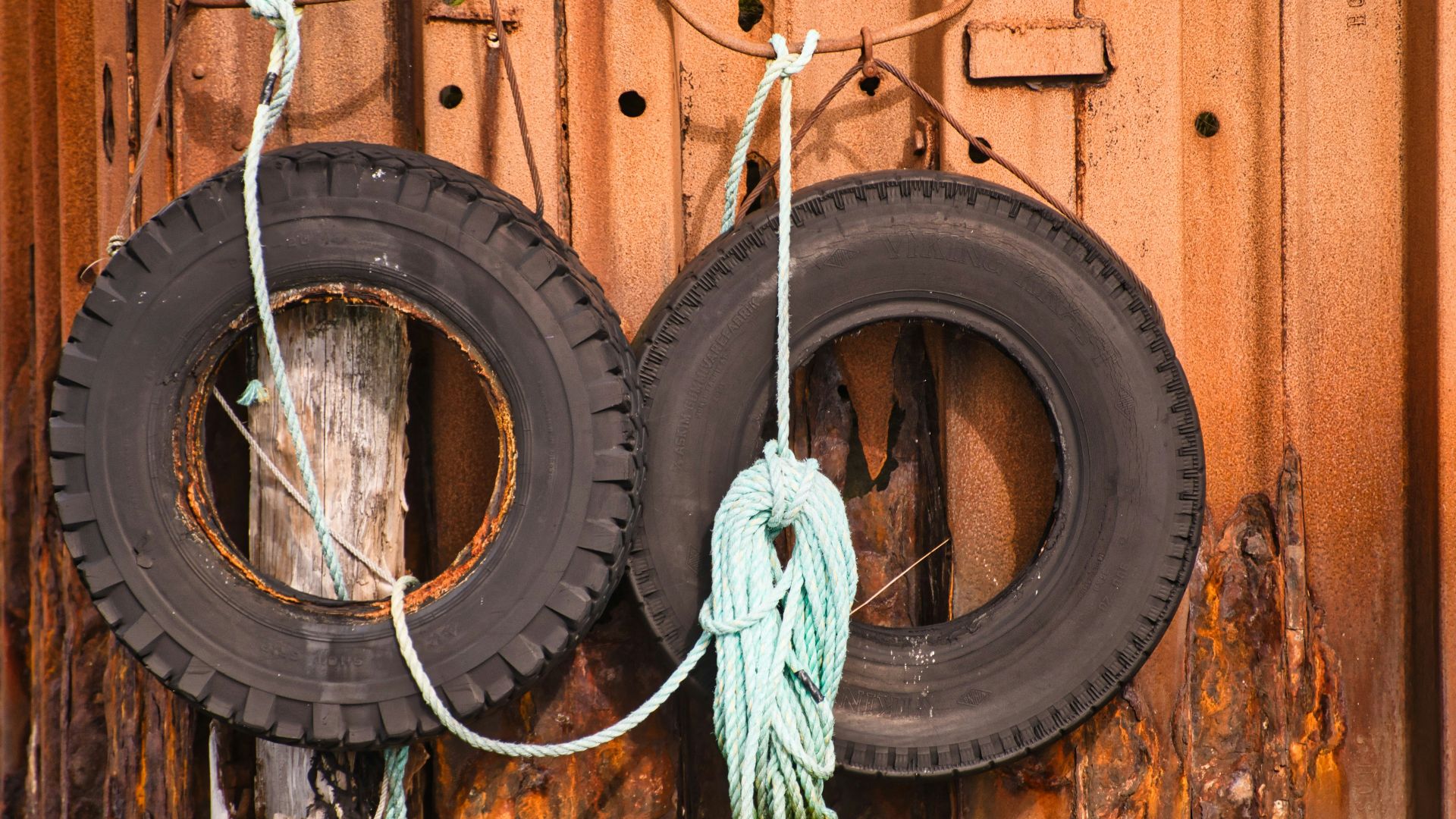 two old tires hanging on a rusty wall