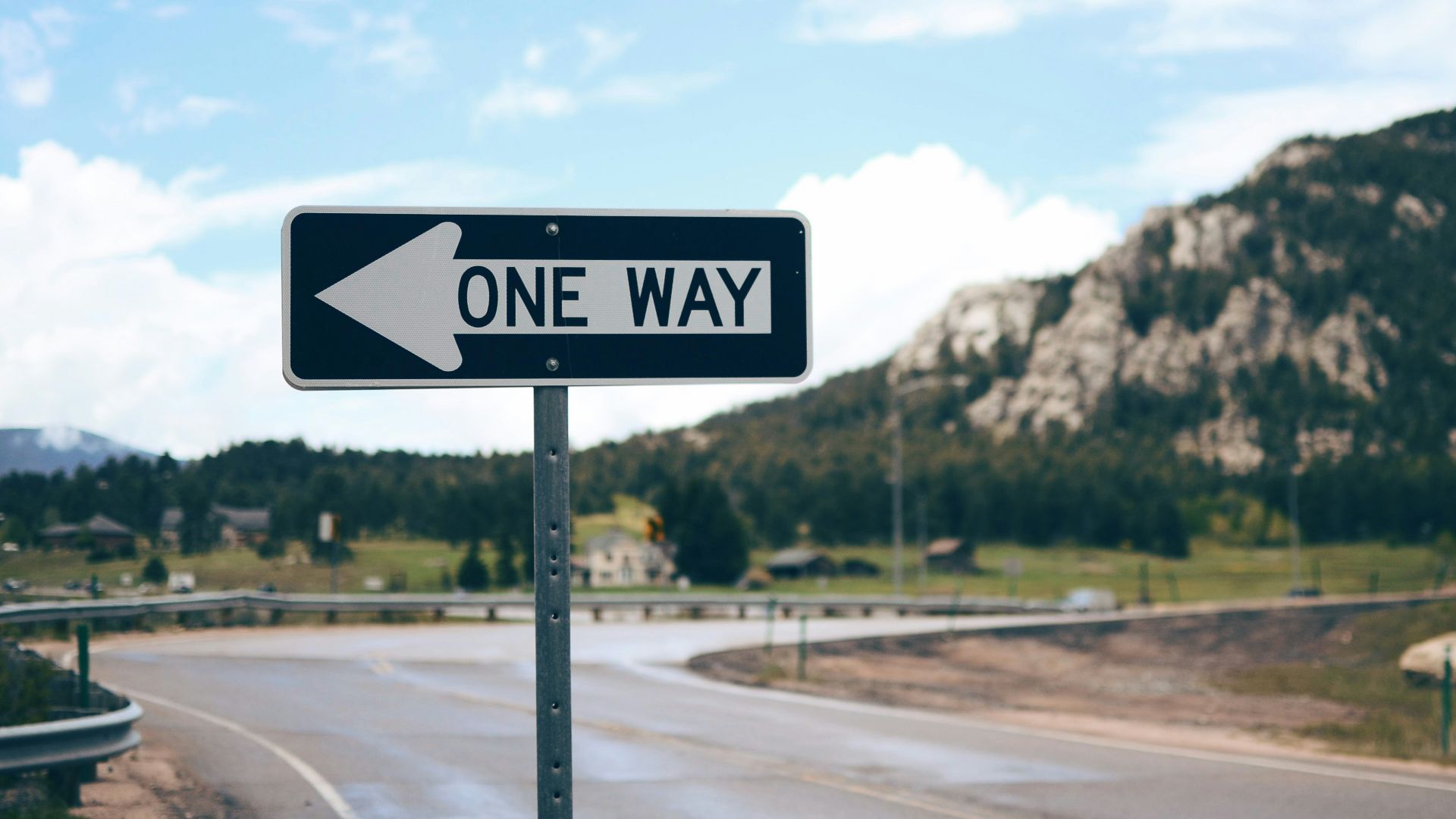 One Way street sign beside road far at the mountain during daytime