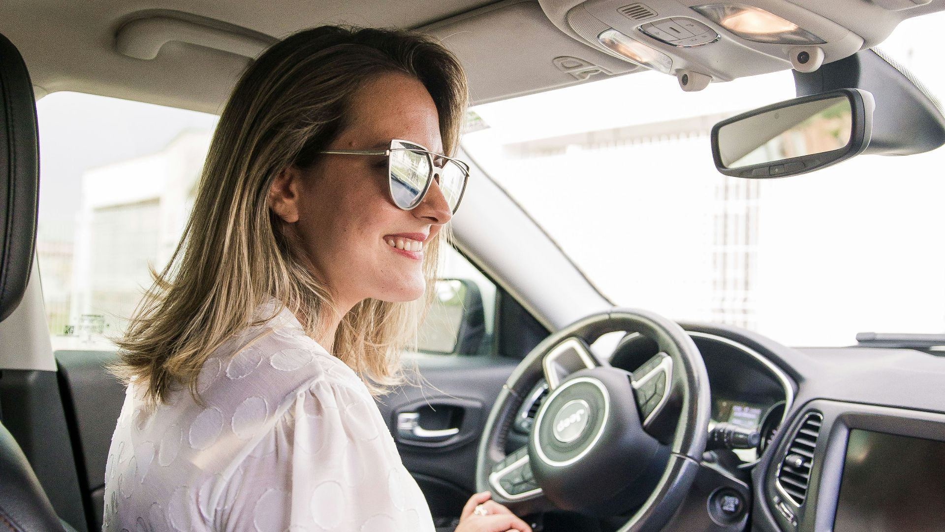 woman in white long sleeve shirt driving car