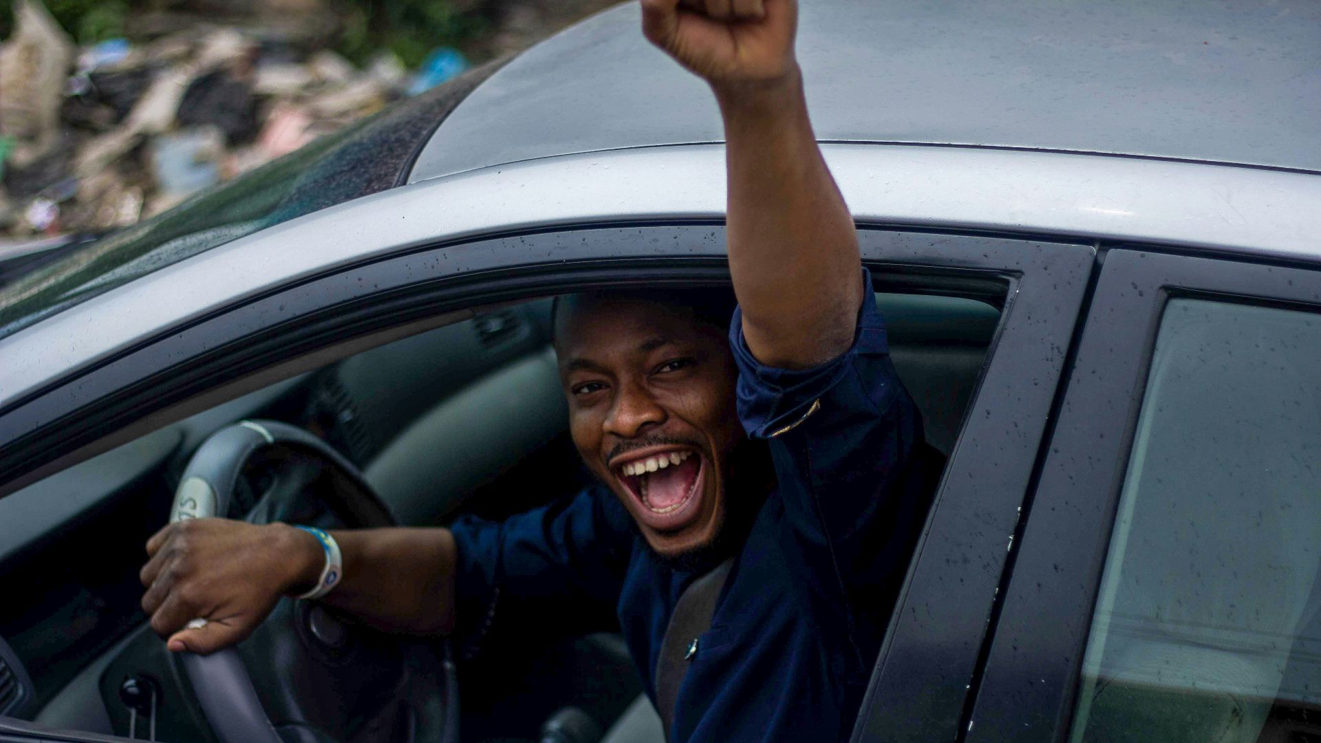 man in black t-shirt and blue denim jeans sitting on car seat