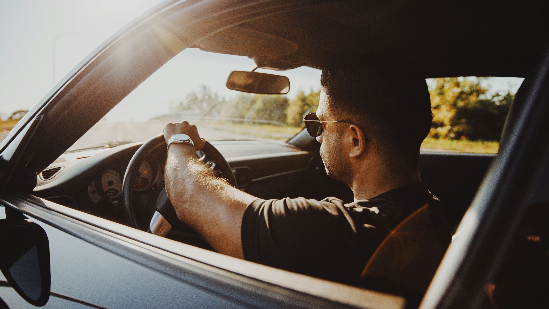 man in black jacket driving car during daytime
