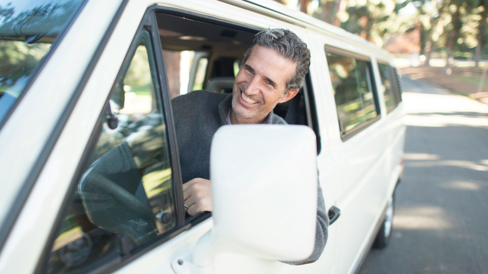 man in gray sweater leaning on van window