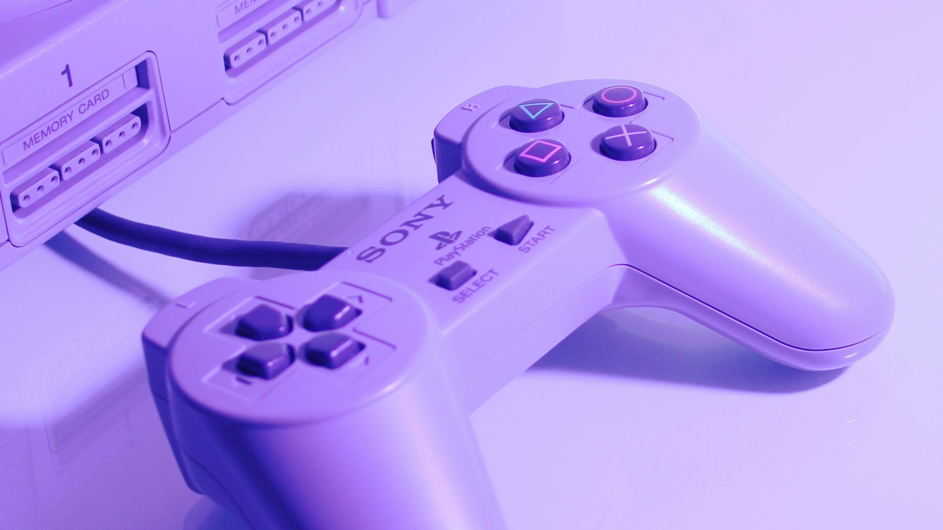 gray Sony PlayStation console with corded controller