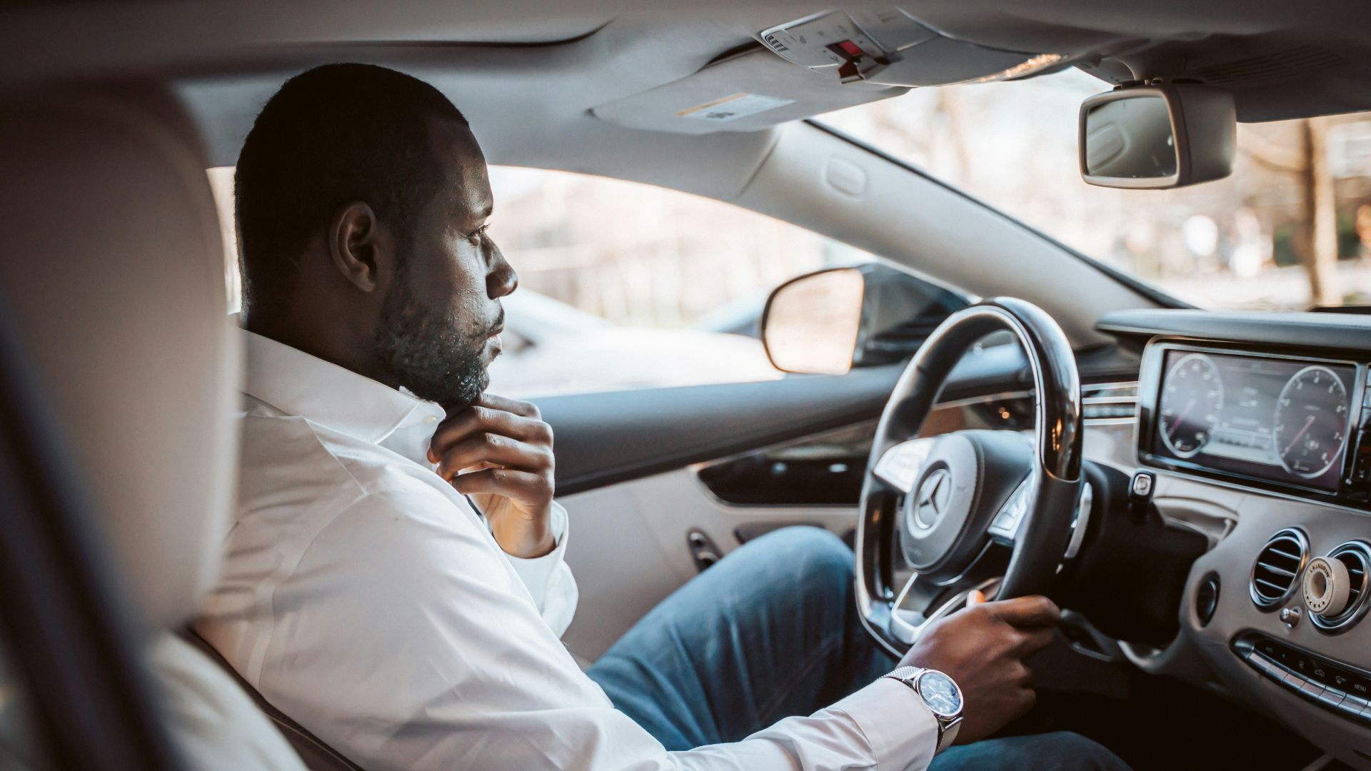 man in white dress shirt driving car during daytime