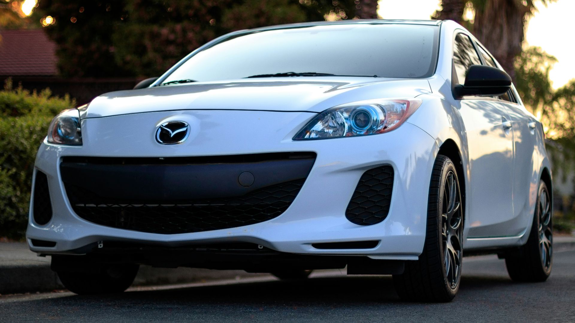 white Mazda sedan on road
