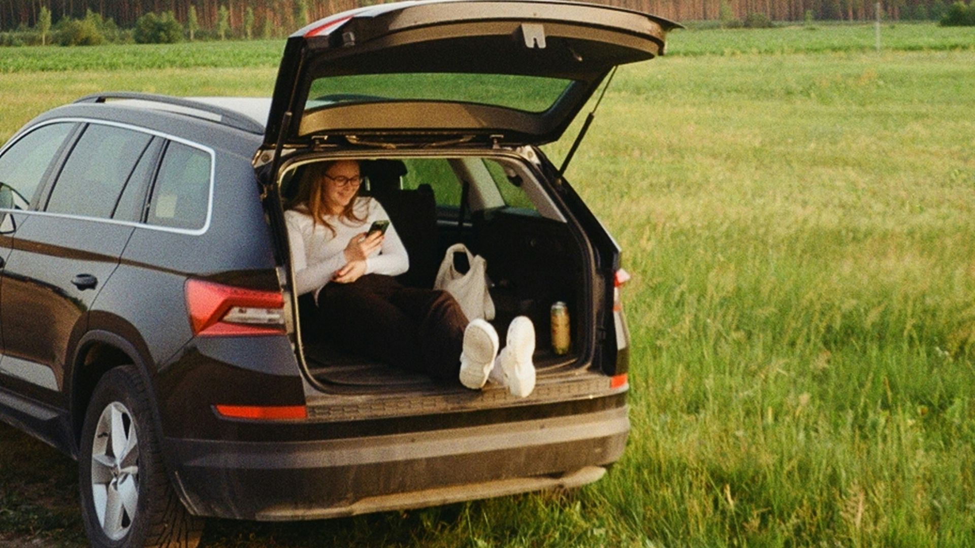 A woman sitting in the back of a car on a dirt road