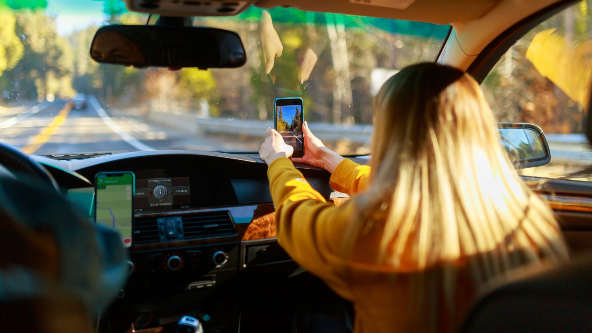 a woman driving a car with a cell phone in her hand