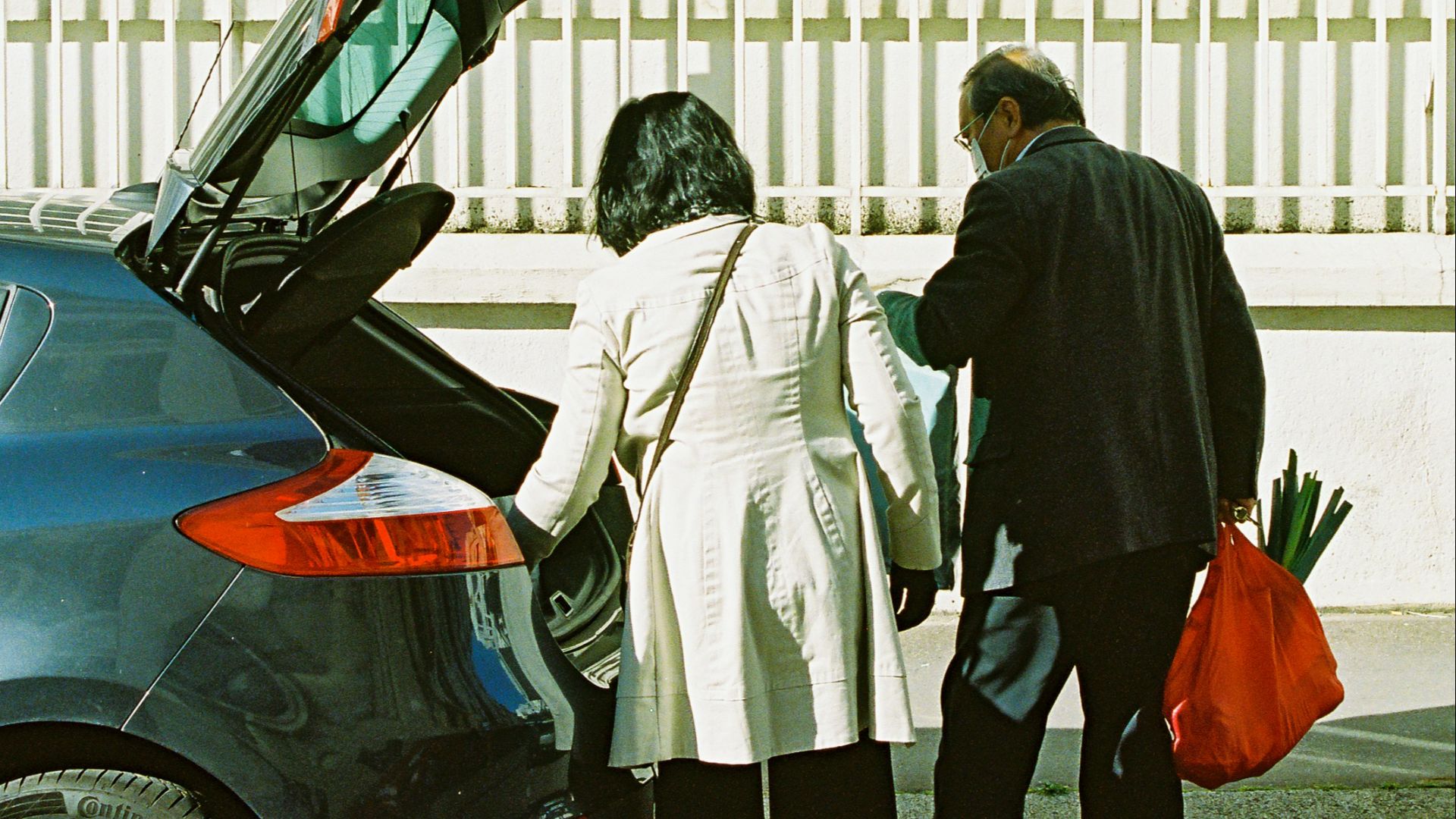 man and woman standing beside black car during daytime