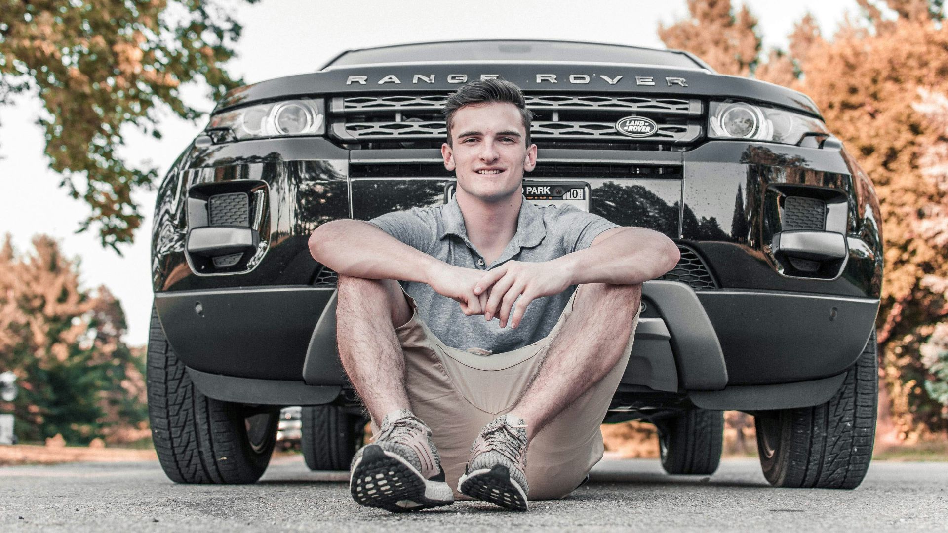 man wearing gray polo shirt in front of Range Rover car