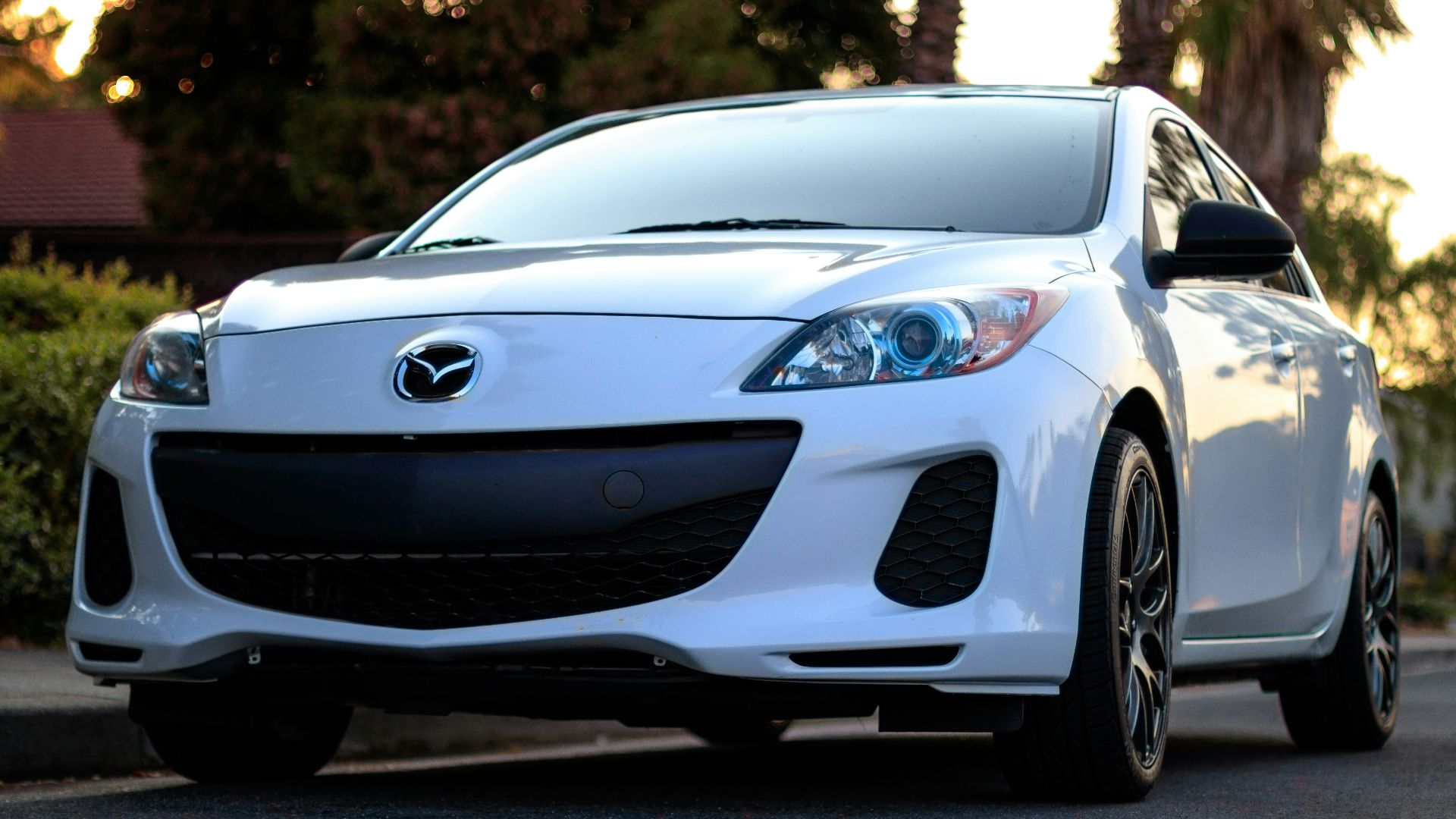 white Mazda sedan on road