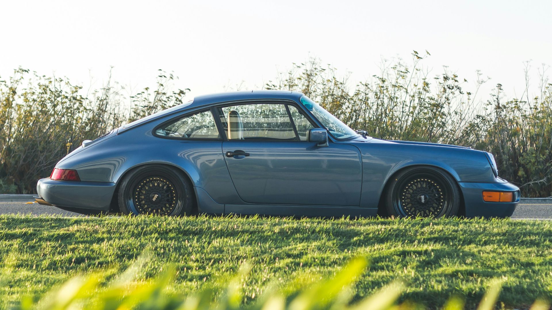 blue Porsche 911 parked beside road