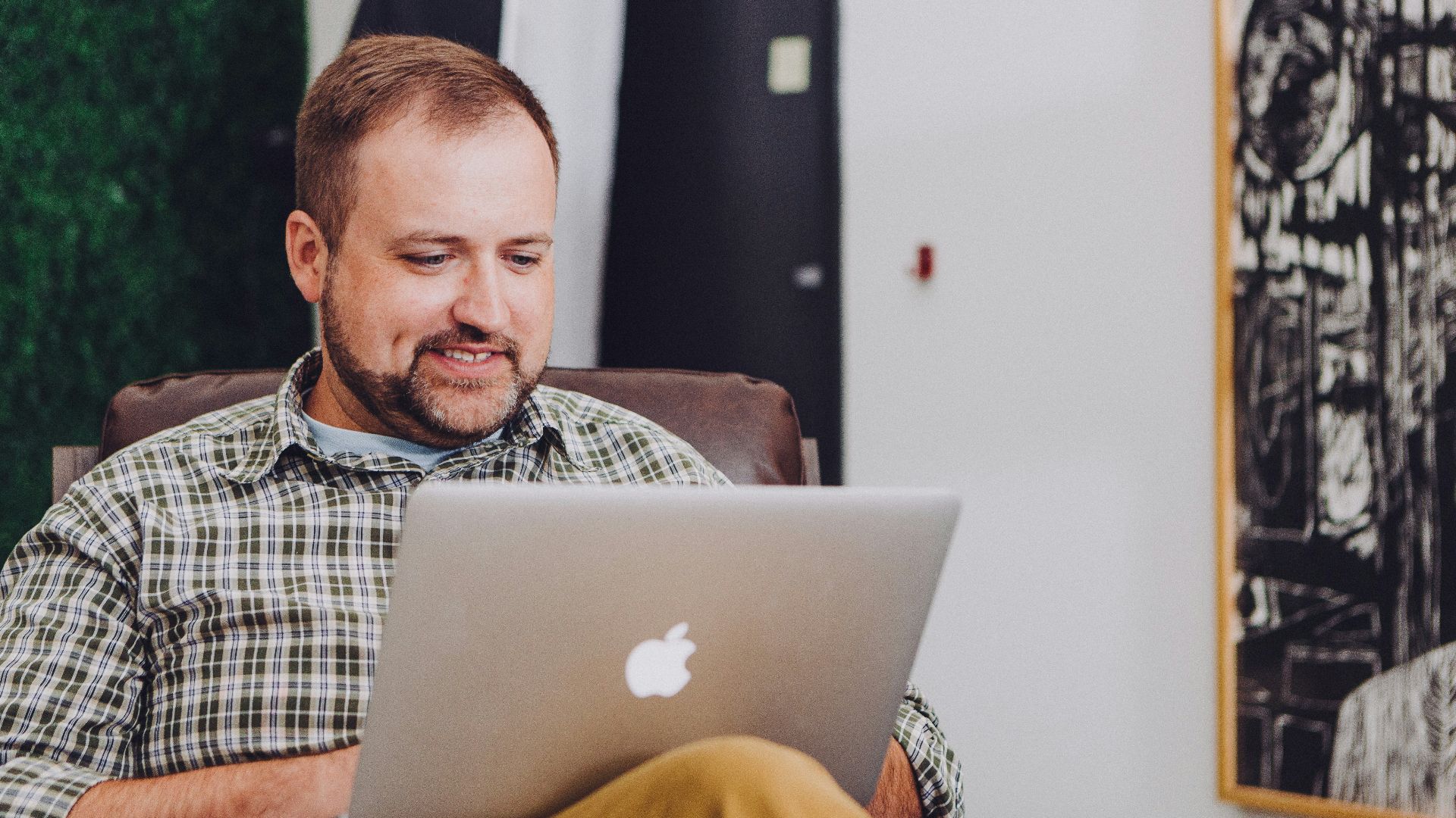 man smiling and using MacBook