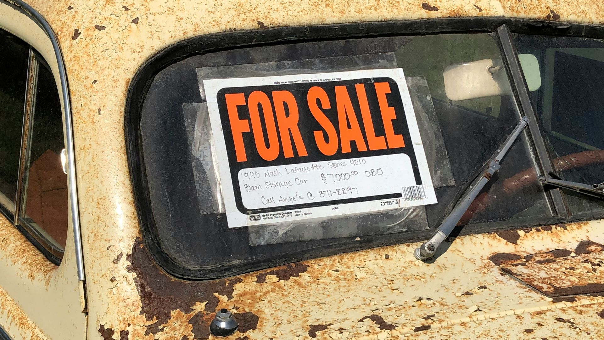 a rusted out car with a for sale sign on it