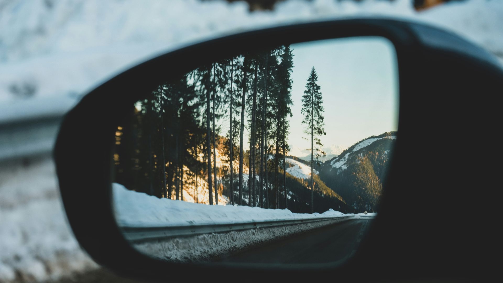 car side mirror showing snow covered trees
