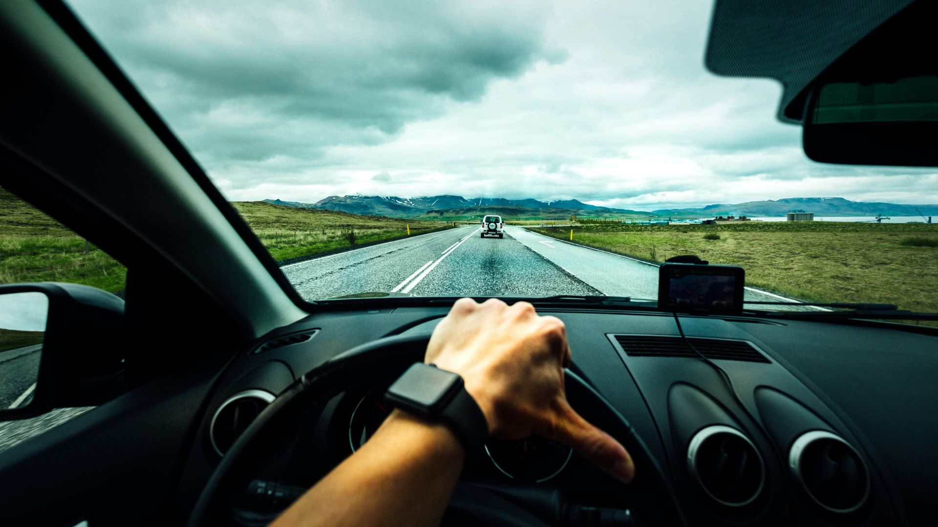 person driving car near vehicle under nimbus cloudes