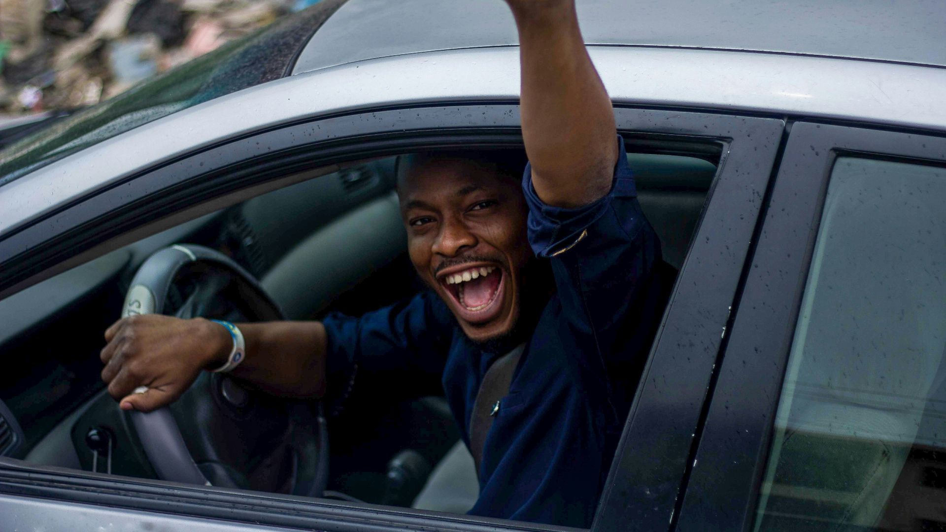 man in black t-shirt and blue denim jeans sitting on car seat