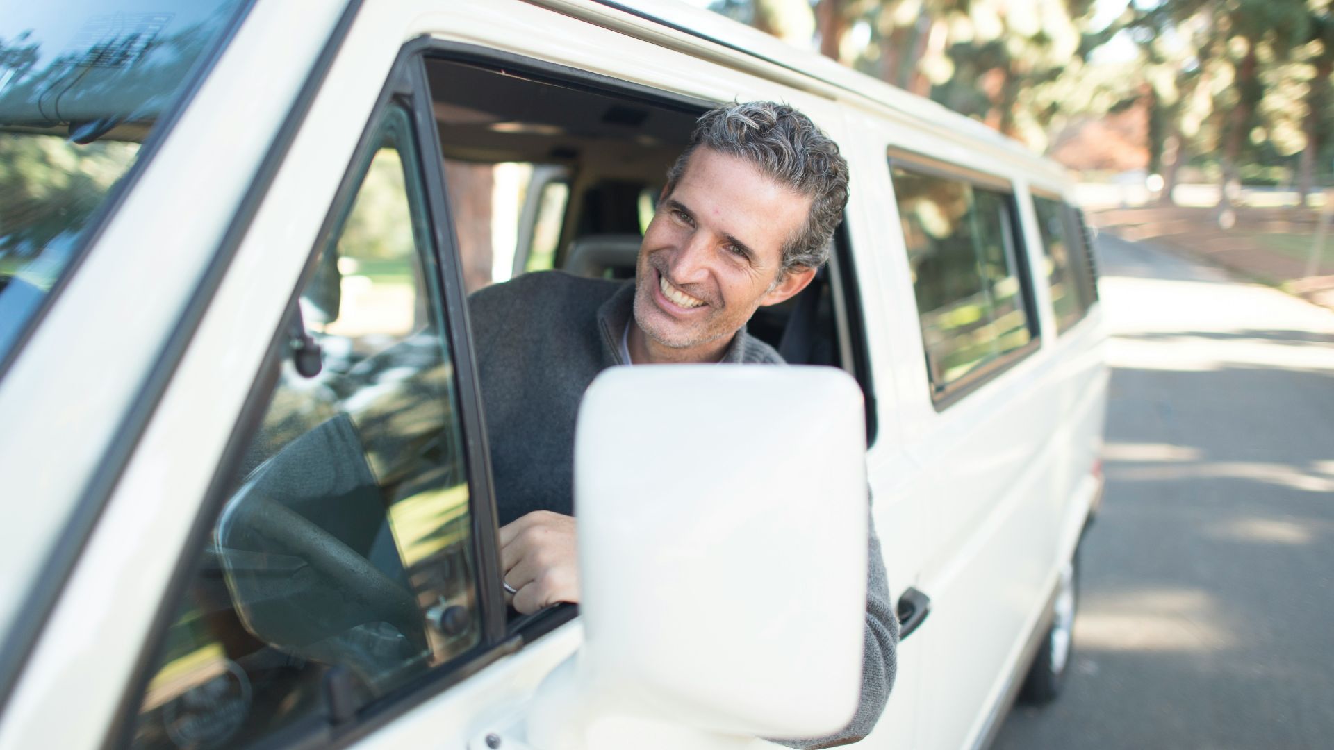 man in gray sweater leaning on van window